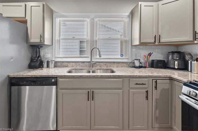 kitchen with light stone counters, decorative backsplash, appliances with stainless steel finishes, and a sink