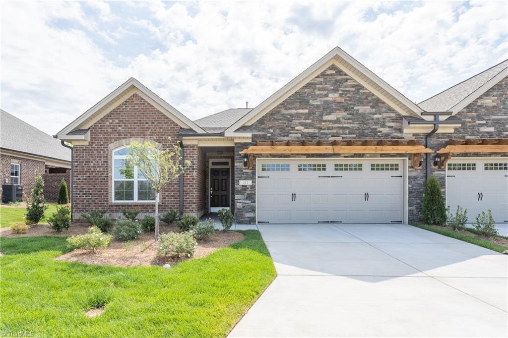 view of front of house with a front yard, central AC unit, and a garage