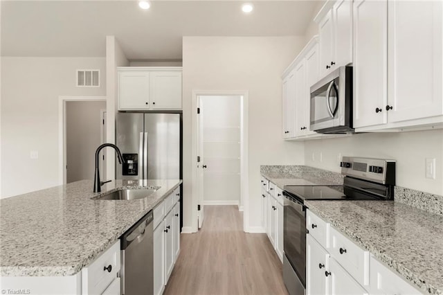 kitchen with light stone countertops, stainless steel appliances, sink, light hardwood / wood-style flooring, and white cabinets