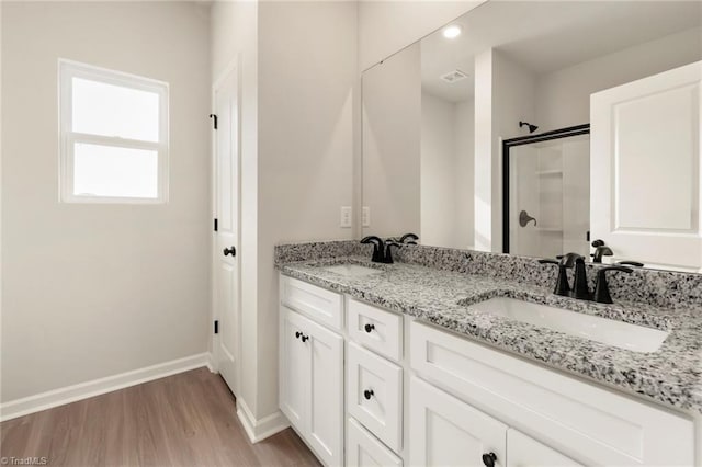 bathroom featuring hardwood / wood-style flooring, vanity, and a shower with door