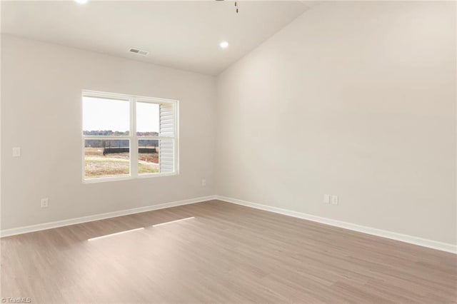 spare room with light hardwood / wood-style floors and vaulted ceiling