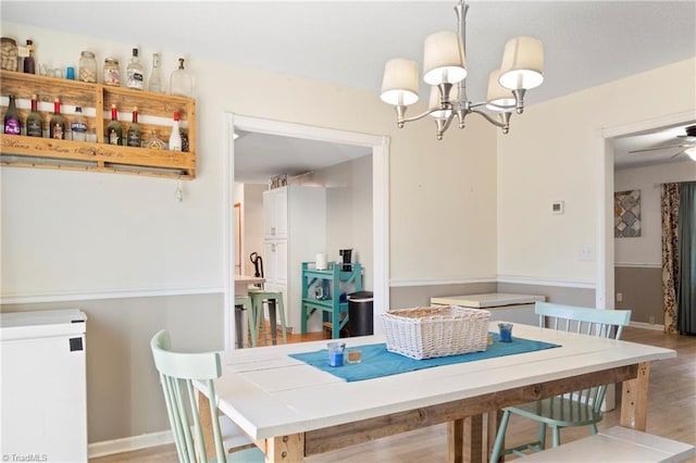 dining space featuring an inviting chandelier, baseboards, and wood finished floors