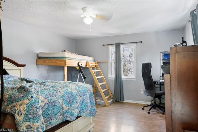 bedroom with a textured ceiling, wood finished floors, a ceiling fan, and baseboards