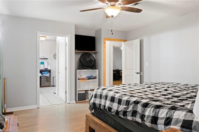 bedroom featuring light wood-type flooring, connected bathroom, a ceiling fan, and baseboards