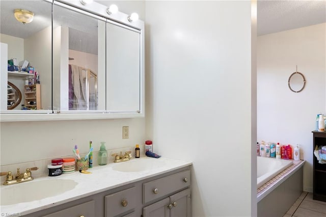 bathroom with a textured ceiling, double vanity, tile patterned flooring, and a sink