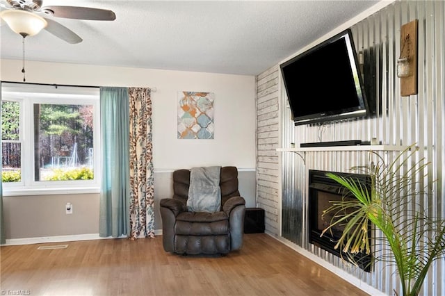 sitting room with baseboards, visible vents, wood finished floors, a textured ceiling, and a fireplace