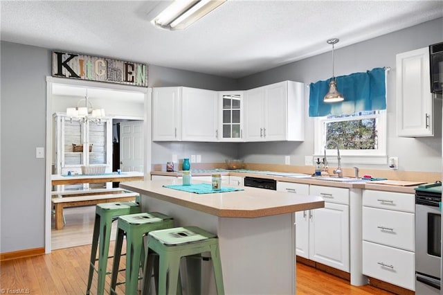 kitchen with light countertops, a sink, white cabinets, and a kitchen breakfast bar