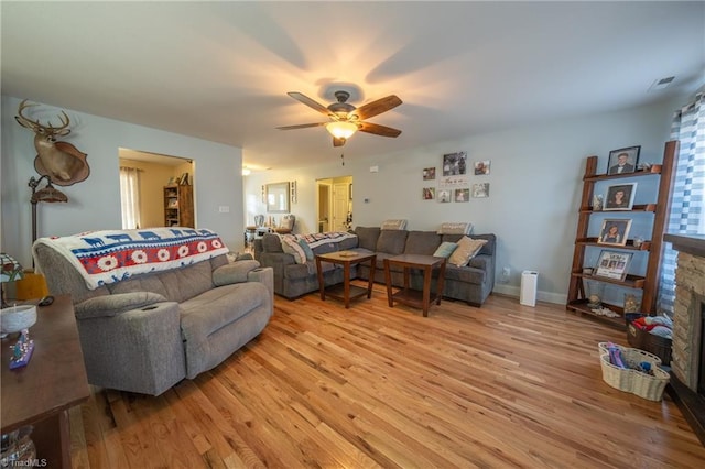 living room featuring a fireplace, light hardwood / wood-style flooring, and ceiling fan