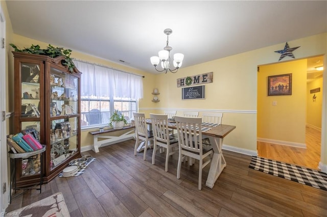 dining space featuring dark hardwood / wood-style floors and a chandelier