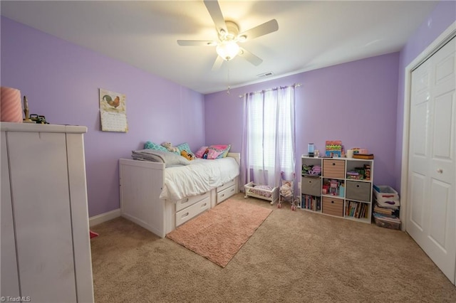 bedroom with ceiling fan, light carpet, and a closet