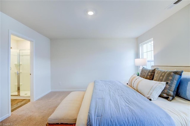 bedroom with ensuite bath and light carpet
