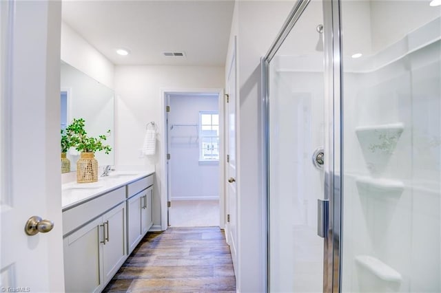 bathroom featuring walk in shower, vanity, and hardwood / wood-style floors