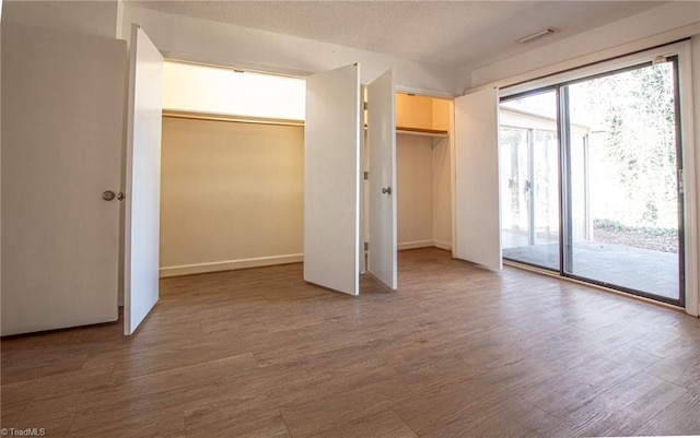 unfurnished bedroom featuring access to exterior and hardwood / wood-style flooring