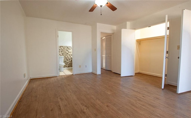 unfurnished bedroom with hardwood / wood-style flooring, ensuite bathroom, and ceiling fan