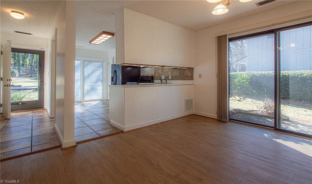 kitchen with hardwood / wood-style flooring, decorative backsplash, and a healthy amount of sunlight