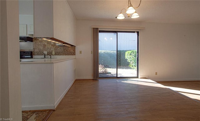 unfurnished dining area featuring hardwood / wood-style floors, a notable chandelier, and a textured ceiling