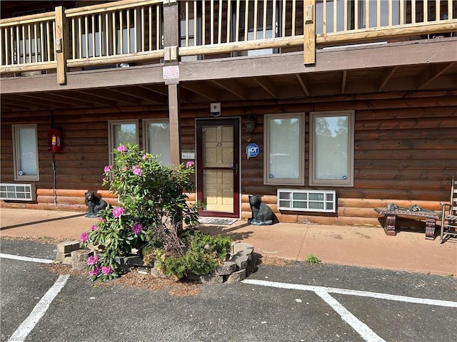 view of exterior entry featuring a balcony and uncovered parking