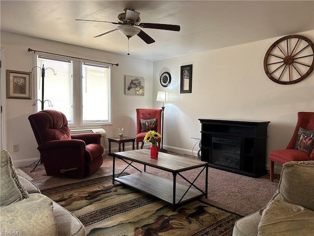 living area with baseboards, a ceiling fan, and a glass covered fireplace
