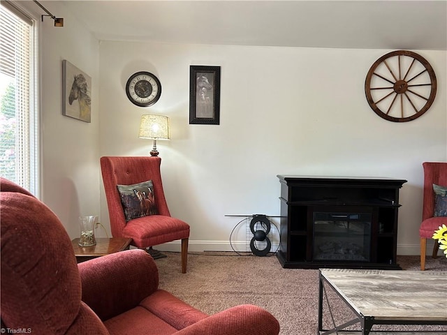 carpeted living area featuring baseboards and a glass covered fireplace