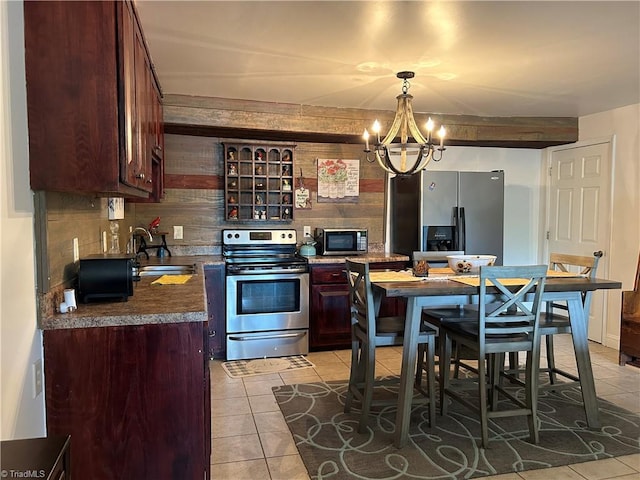 kitchen featuring stainless steel appliances, light tile patterned floors, a sink, a chandelier, and decorative light fixtures