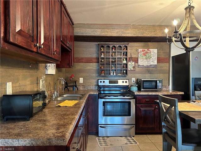 kitchen with stainless steel appliances, a sink, a chandelier, light tile patterned floors, and dark brown cabinets