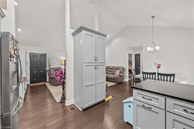 kitchen featuring high vaulted ceiling, dark wood-style flooring, open floor plan, stainless steel refrigerator with ice dispenser, and pendant lighting