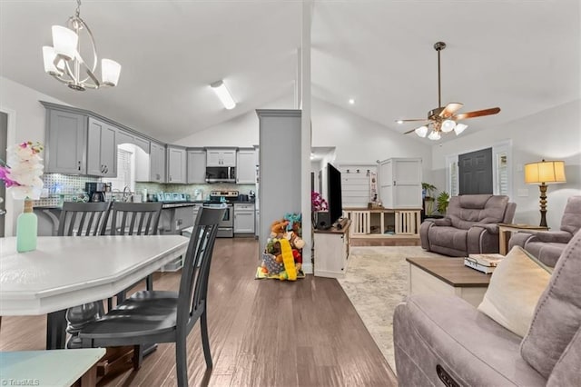 dining space featuring high vaulted ceiling, dark wood finished floors, and ceiling fan with notable chandelier