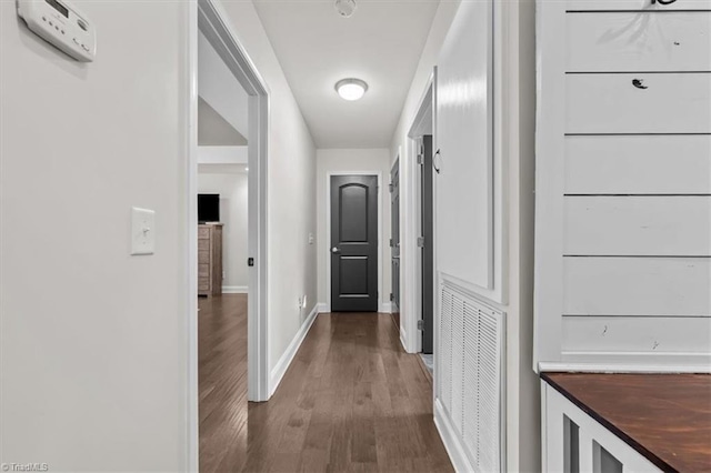 hall featuring baseboards, visible vents, and dark wood-type flooring