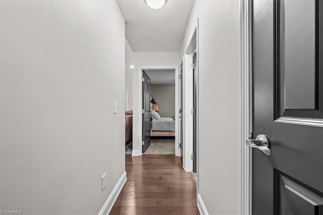 corridor with baseboards and dark wood finished floors