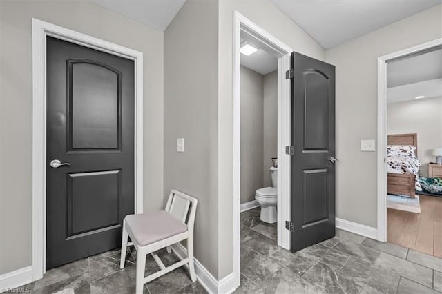 bathroom with toilet, ensuite bath, and baseboards