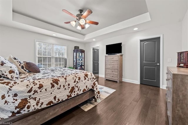 bedroom featuring baseboards, dark wood finished floors, a ceiling fan, a tray ceiling, and recessed lighting