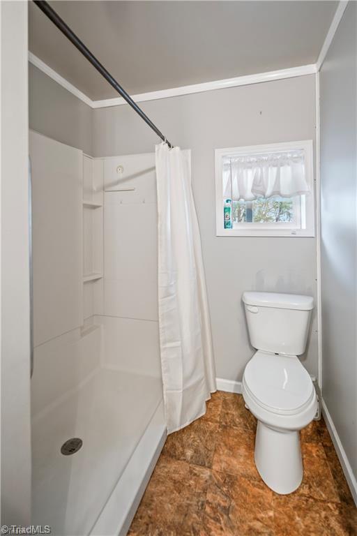 bathroom with curtained shower, baseboards, and toilet