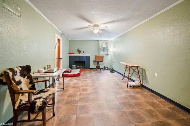 sitting room with a textured ceiling, a fireplace, ornamental molding, and a ceiling fan