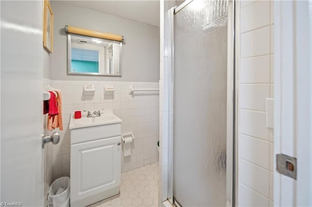 bathroom with a stall shower, a wainscoted wall, tile walls, and vanity