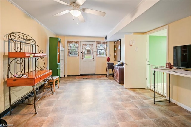 foyer with ornamental molding, a ceiling fan, and baseboards