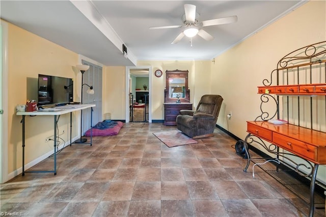 sitting room with baseboards, a ceiling fan, and crown molding