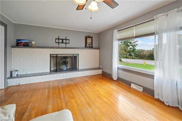 unfurnished living room with crown molding, a fireplace, visible vents, wood finished floors, and baseboards