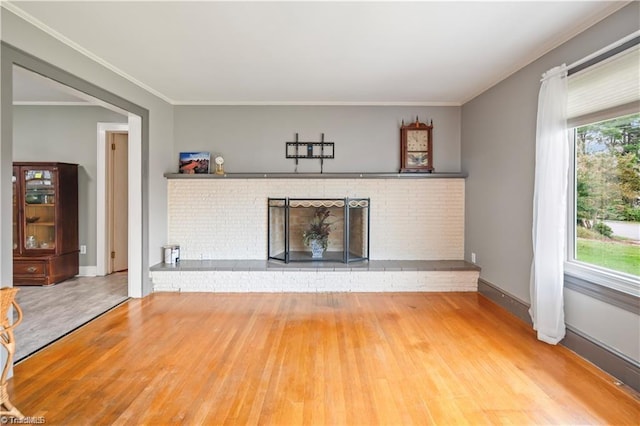 unfurnished living room with crown molding, a fireplace, baseboards, and wood finished floors