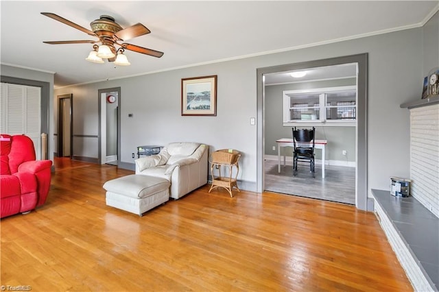 living room with a ceiling fan, baseboards, ornamental molding, and wood finished floors