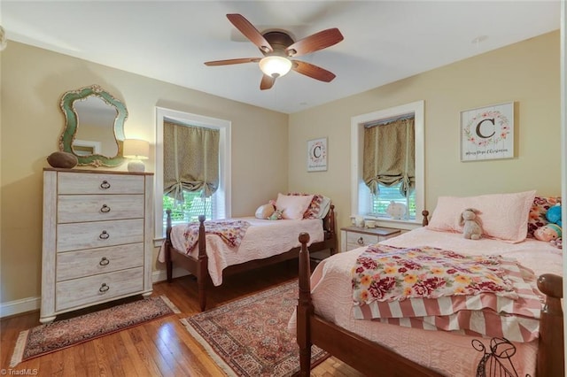 bedroom with multiple windows, wood-type flooring, and ceiling fan