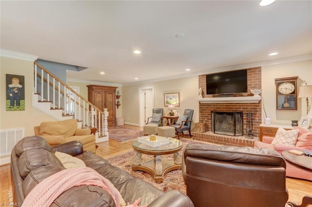 living room with brick wall, light hardwood / wood-style flooring, a brick fireplace, and ornamental molding