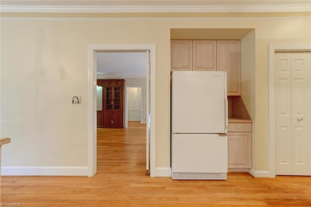 kitchen with light hardwood / wood-style floors, white fridge, and crown molding