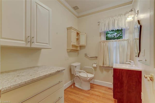 bathroom with ornamental molding, wood-type flooring, vanity, and toilet