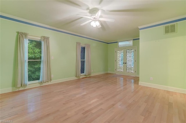 empty room featuring ceiling fan, french doors, light wood-type flooring, and crown molding