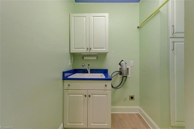 clothes washing area featuring hookup for an electric dryer, light wood-type flooring, hookup for a washing machine, cabinets, and sink