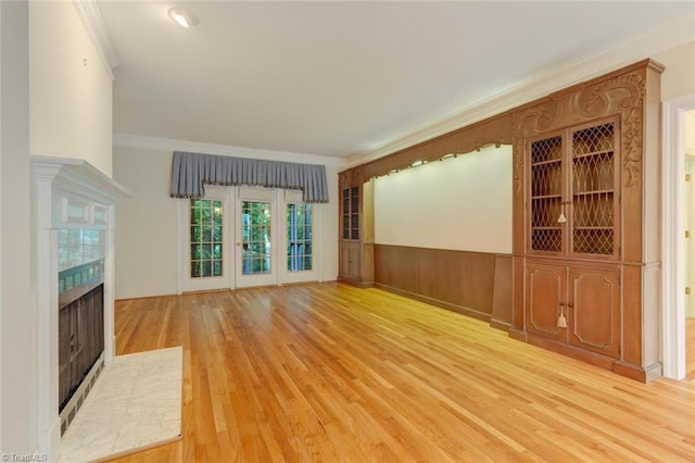 unfurnished living room with a tiled fireplace, light hardwood / wood-style floors, ornamental molding, and wood walls