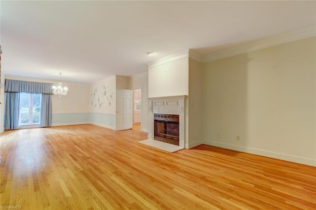 unfurnished living room featuring light wood-type flooring, crown molding, and a chandelier