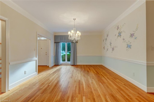 empty room with a notable chandelier, ornamental molding, and hardwood / wood-style flooring