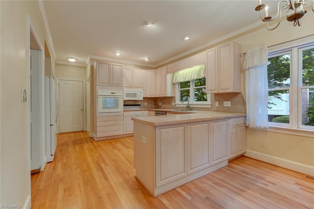 kitchen featuring white appliances, a chandelier, light wood-type flooring, kitchen peninsula, and sink