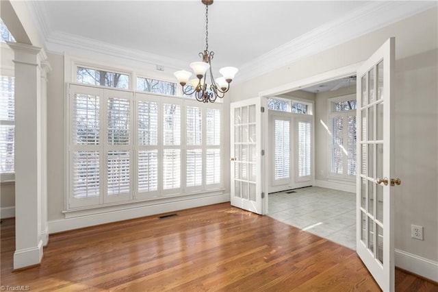 unfurnished dining area featuring wood finished floors, a healthy amount of sunlight, french doors, and ornamental molding